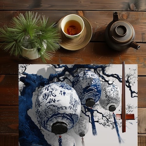 Puede incluir: Vista aérea de una mesa de madera con un juego de té y faroles decorativos. Los faroles son blancos con diseños azules y texto. También hay una pequeña planta en maceta y una taza de té.