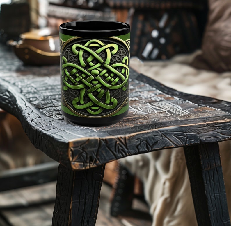 May include: A black ceramic mug with a green Celtic knot design. The mug is sitting on a dark wooden table.