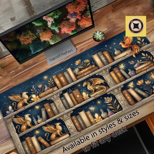 May include: A rectangular desk mat featuring a dark blue background with a fantasy library design. The print includes stone shelves, rows of leather-bound books, golden griffins, a dragon, glowing crystals, potion bottles, and flowers.