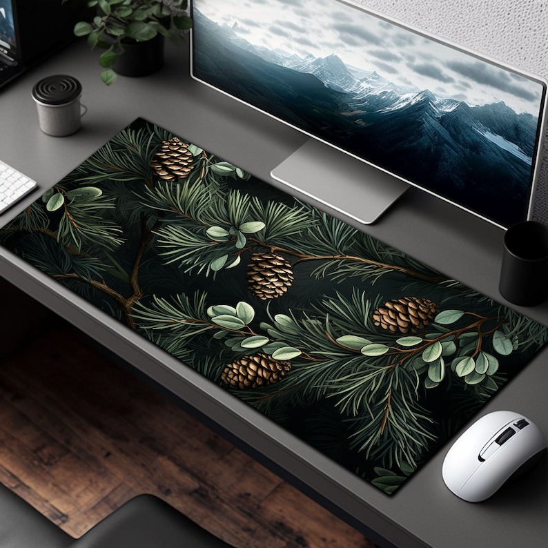 May include: A dark green and black mousepad with a pine branch design featuring gold pine cones. The design is detailed and realistic.