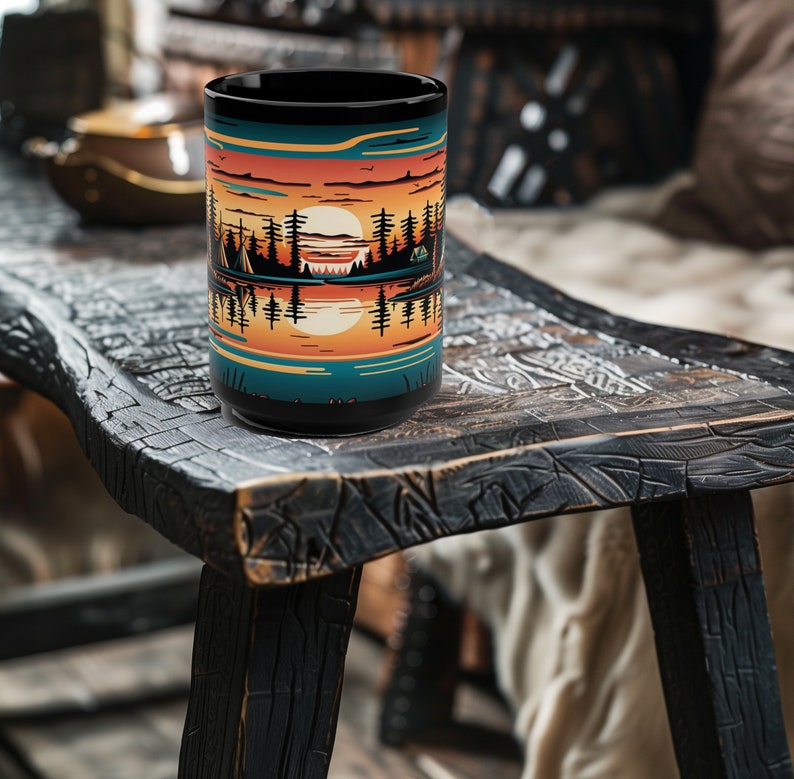 May include: A black ceramic mug with a colorful sunset scene and trees reflected in a lake. The mug is sitting on a rustic wooden table.