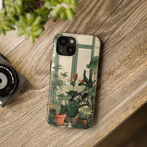 May include: A phone case featuring a botanical illustration of plants in a greenhouse. The case has a white background with a green, brown, and red colour scheme. The case has a camera lens cutout.