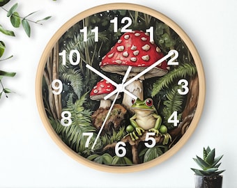 May include: A round wooden clock with a green, white, and red forest scene. The clock face features white numbers and hands, and the scene includes a red and white mushroom, a green frog, and green ferns.