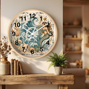 May include: A round wall clock with a light wood frame featuring a detailed illustration of a mermaid swimming amidst blue ocean waves, seashells, and starfish. The clock face displays black Arabic numerals from 1 to 12 and white clock hands.