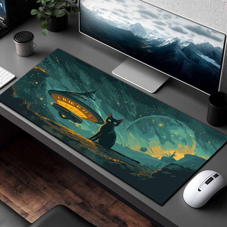 May include: A black cat sits on a green and blue galaxy-themed mousepad with a flying saucer in the background. The mousepad has a starry night sky design with a large planet in the distance.