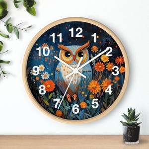 May include: A round wooden wall clock with a blue and orange owl design. The clock face has white numbers and hands. The owl is surrounded by flowers and leaves.
