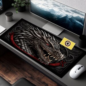 May include: Black and red dragon mousepad with intricate details. The dragon has a fierce expression with sharp teeth and a red eye. The mousepad is on a desk with a computer monitor and a mouse.