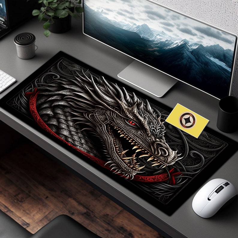 May include: Black and red dragon mousepad with intricate details. The dragon has a fierce expression with sharp teeth and a red eye. The mousepad is on a desk with a computer monitor and a mouse.