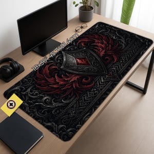 May include: A black and red gaming mouse pad with a shield and feather design. The mouse pad measures 18x36 inches (45.7x91.4cm). The design features a shield with a red gem and ornate detailing.