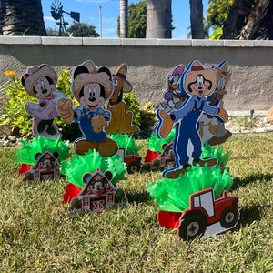 以下が含まれることがあります： ミッキーマウスとその仲間たちをフィーチャーした、農場をテーマにしたセンターピースが5つ。各センターピースには、キャラクターの切り抜き、赤い納屋のベース、緑の草のような素材が含まれています。