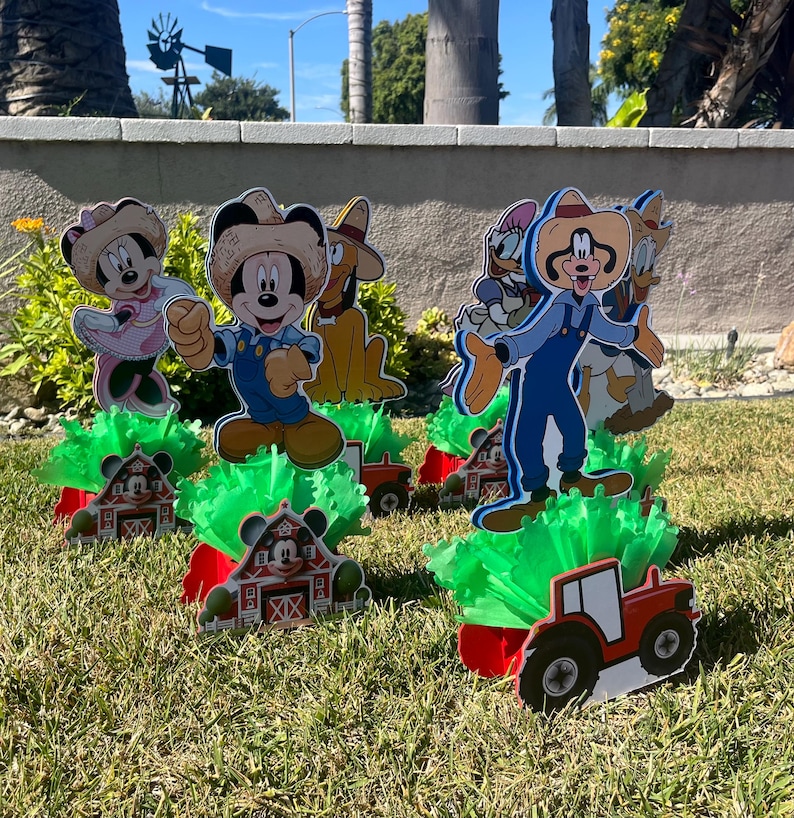 以下が含まれることがあります： ミッキーマウスとその仲間たちをフィーチャーした、農場をテーマにしたセンターピースが5つ。各センターピースには、キャラクターの切り抜き、赤い納屋のベース、緑の草のような素材が含まれています。