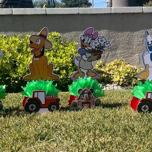 以下が含まれることがあります： ミッキーマウス、ドナルドダック、グーフィー、プルートをフィーチャーした、農場をテーマにしたセンターピース6個セット。各センターピースには、キャラクターの切り抜き、緑色のベース、赤いトラクターが含まれています。