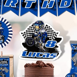 Pu&ograve; includere: Un topper per torta di compleanno a tema motocross blu e nero con un pilota di cartoni animati su una moto da cross, bandiere a scacchi e il nome "Lucas" e il numero "8" in blu.