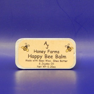 May include: A rectangular tin of Happy Bee Balm from Honey Farms, with a light brown label and a blue background. The label features two cartoon bees and the text "Happy Bee Balm." The net weight is 0.20 oz.