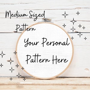 May include: A white embroidery hoop with the text "Your Personal Pattern Here" on a white wooden background with small black stars.