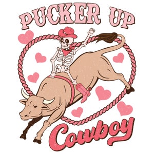 May include: A skeleton wearing a pink cowboy hat rides a brown bull with a pink rope. The text "Pucker Up Cowboy" is written in pink letters.