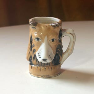 May include: A set of three ceramic mugs with a speckled, matte finish. The mugs are in shades of cream, light gray, and dark gray. Each mug has a simple, minimalist design, perfect for coffee or tea.