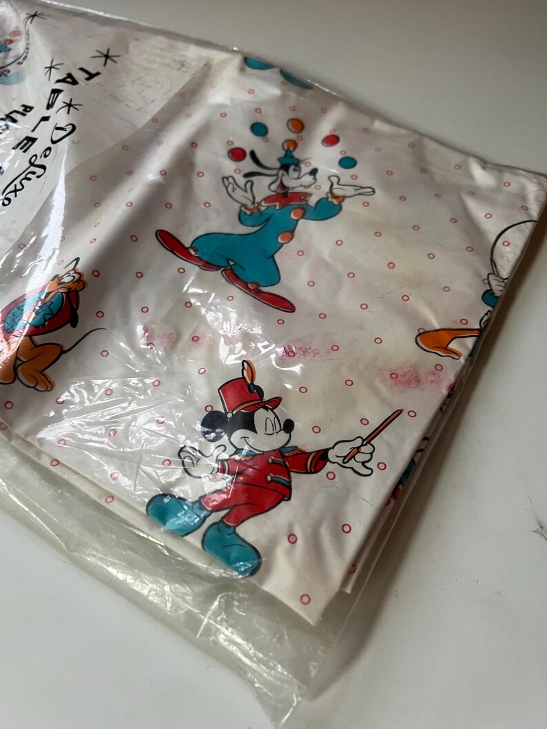 Puede incluir: Juego de s&aacute;banas blancas con los personajes de dibujos animados Goofy, Mickey Mouse y Pluto. La s&aacute;bana tiene un estampado de lunares rojos. Goofy hace malabarismos con bolas de colores y Mickey Mouse lleva un uniforme rojo. El juego est&aacute; en un paquete de pl&aacute;stico.
