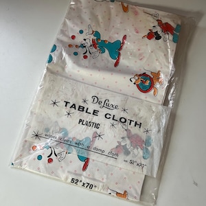 Puede incluir: Un mantel de pl&aacute;stico vintage con Mickey Mouse y sus amigos en un dise&ntilde;o l&uacute;dico. La tela blanca tiene un patr&oacute;n de lunares rojos y personajes de dibujos animados. El paquete dice "Deluxe Table Cloth" y mide 132cm x 178cm.