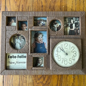 Puede incluir: Un marco de fotos de madera marrón con un reloj en el centro y múltiples ranuras para fotos más pequeñas. La esfera del reloj es blanca con números y manecillas negros. El marco tiene el texto "foto folio by New Haven" impreso en la parte inferior.