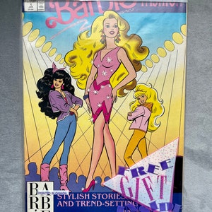 May include: A Barbie comic book in a plastic sleeve. The cover features three Barbie figures in stylish outfits, with the main Barbie in a pink dress. The comic has the text "Barbie" and "Stylish Stories and Trend-Setting". A "Free Gift Inside" sticker is visible.