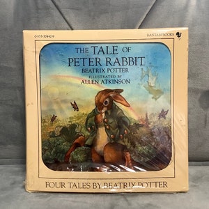 May include: A hardcover book titled "The Tale of Peter Rabbit" by Beatrix Potter, illustrated by Allen Atkinson. The cover art features a brown rabbit in a green jacket, surrounded by foliage and butterflies. The book is from Bantam Books and includes "Four Tales by Beatrix Potter."