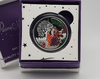 May include: A silver coin in a purple box with a white background and stars. The coin features a colorful image of a couple in a winter scene.