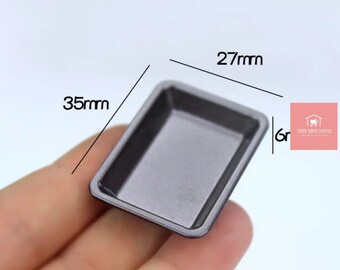 May include: A small, black, rectangular baking pan measuring 27mm by 35mm.  The pan is made of metal and has a smooth, shiny surface.