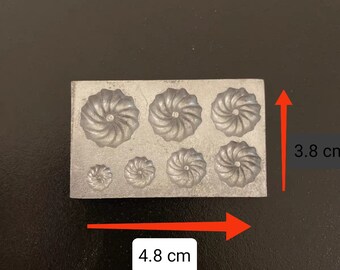 May include: A metal mold with eight different sized and shaped cavities for making decorative items. The mold is 4.8 inches wide and 3.8 inches tall.