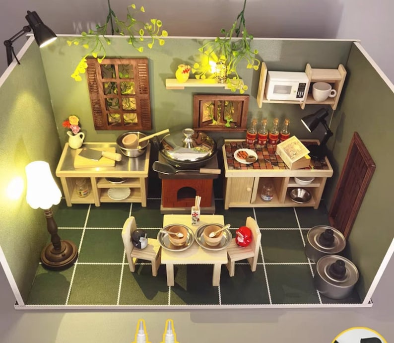 Op de afbeelding: Miniatuurkeukendiorama met een groen en wit betegelde vloer. De sc&egrave;ne omvat een fornuis, magnetron, tafelsetting en diverse keukengerei. De muren zijn groen geschilderd en de sc&egrave;ne wordt verlicht door kleine lampen.