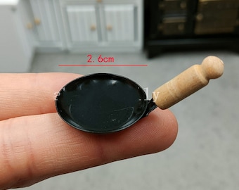 May include: A miniature black frying pan with a wooden handle. The pan is 2.6 inches in diameter.
