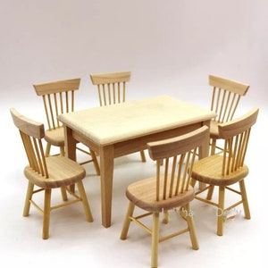 May include: A miniature wooden dining set with a rectangular table and six chairs. The set is made of light brown wood and has a simple, classic design.