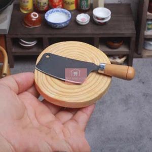 May include: A miniature wooden chopping board with a small silver knife on top. The knife has a wooden handle. The chopping board is approximately 10 cm in diameter.