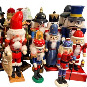May include: A collection of wooden nutcracker figurines featuring various characters including Santa Claus, a wizard with a star-patterned hat, a soldier in a black helmet, and figures in colorful uniforms, all standing on individual wooden bases.