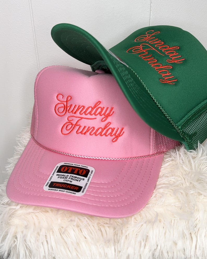 May include: Two trucker hats, one pink and one green, with the embroidered text "Sunday Funday" in a cursive font. The pink hat has a white tag that reads "OTTO WORLD FAMOUS FOAM FRONT".