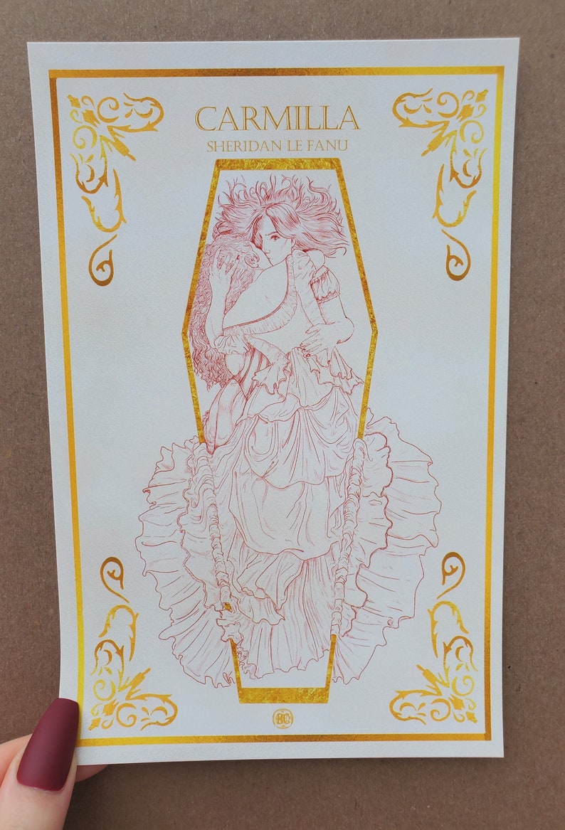 May include: A white print with a gold border featuring a red line drawing of a woman in a coffin. The title "Carmilla" and the author "Sheridan Le Fanu" are printed in gold at the top of the print.