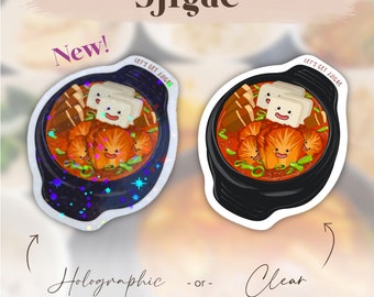 Può includere: Due versioni di un adesivo con un'illustrazione di cartone animato di uno stufato coreano chiamato "Jjigae". L'adesivo è disponibile in finiture olografiche e trasparenti. Il testo "Let's Get Jjigae" è stampato sull'adesivo.