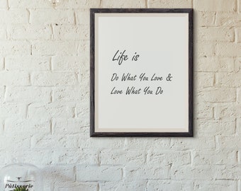May include: A framed print with the text "Life is Do What You Love & Love What You Do" hangs on a white brick wall. A table holds a teacup, a decorative container, and a glass-domed cake stand.