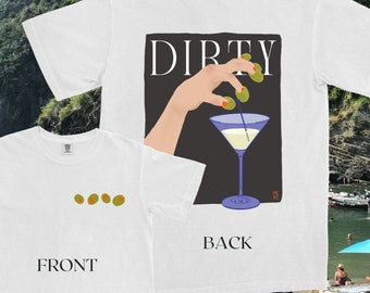May include: White t-shirt with a graphic of a hand placing olives in a martini glass. The text "DIRTY" is printed above the graphic. The back of the shirt has the word "BACK" printed on it. The front of the shirt has three olives printed on it. The text "FRONT" is printed below the olives.