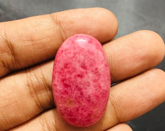 May include: A pink oval cabochon gemstone with a marbled pattern.