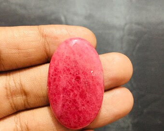 May include: A pink oval-shaped gemstone with a textured surface.