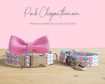 May include: Pink dog collar and leash set with a matching bow tie. The collar and leash feature a floral pattern with pink, blue, and orange flowers on a white background. The bow tie is a solid pink color. The collar has a gold-colored buckle with the name "Charlie" and a phone number.