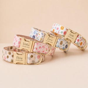May include: Four floral patterned dog collars with gold-colored buckles. Each collar is personalized with a name and phone number. The collars feature a variety of pastel floral designs, including pink, blue, and white.