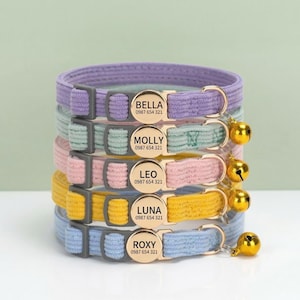 May include: Five pastel-coloured cat collars in shades of purple, green, pink, yellow, and blue. Each collar has a gold buckle with a name and phone number. Gold bells hang from the collars.
