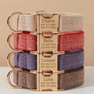 May include: A stack of four pet collars with a herringbone fabric pattern in beige, red, purple, and brown. Each collar features a gold-toned metal side-release buckle engraved with a name and two phone numbers: Charlie, Bella, Cooper, and Luna.