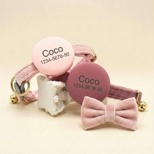 May include: Two velvet pet collars in shades of light and dark pink, each featuring a round tag engraved with the name Coco and the number 1234-5678-90. The collars include gold-toned metal hardware, a small bell, and a matching pink velvet bow tie.