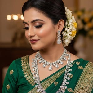 May include: A woman wearing a green sari and diamond jewellery. The jewellery includes a necklace and earrings. The sari has gold embroidery. The woman has flowers in her hair.