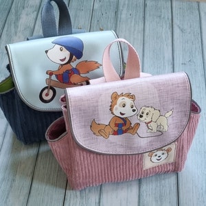 Op de afbeelding: Twee kleine, kleurrijke, stoffen rugzakken met dierenfiguren. De blauwe rugzak heeft een eekhoorn die op een fiets rijdt en de roze rugzak heeft een eekhoorn en een hond. Beide rugzakken hebben een ritssluiting en een bovenste handvat.