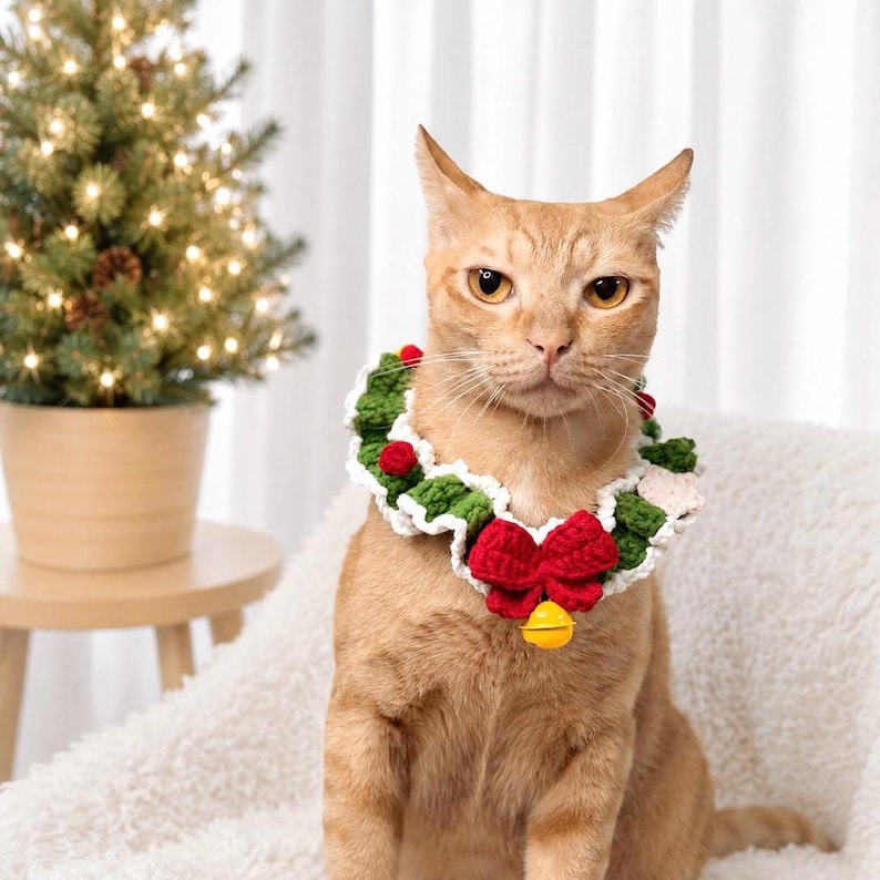 May include: A crocheted pet collar featuring a green and white ruffled design with small red pom-poms, a prominent red bow, and a single yellow bell attached at the center. The collar is worn around the neck of an orange tabby cat.
