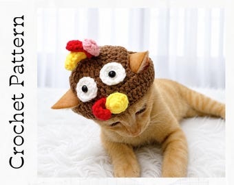 May include: A brown crochet hat designed to look like a turkey, featuring two white circular eyes with black pupils, a yellow beak, and red and pink accents on top. The text Crochet Pattern is printed vertically on the left side of the image.